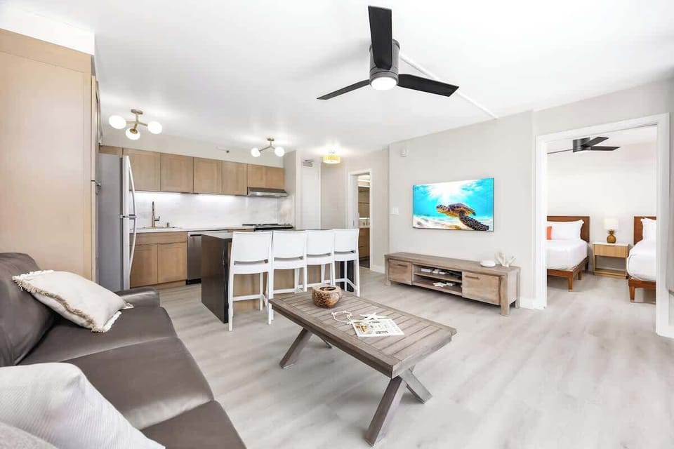 Enjoy your stay in your open-concept living space that features a comfortable sofa with a mounted 55" Samsung smart TV, a sleek kitchen with an island/breakfast bar, and easy access to your bedroom.