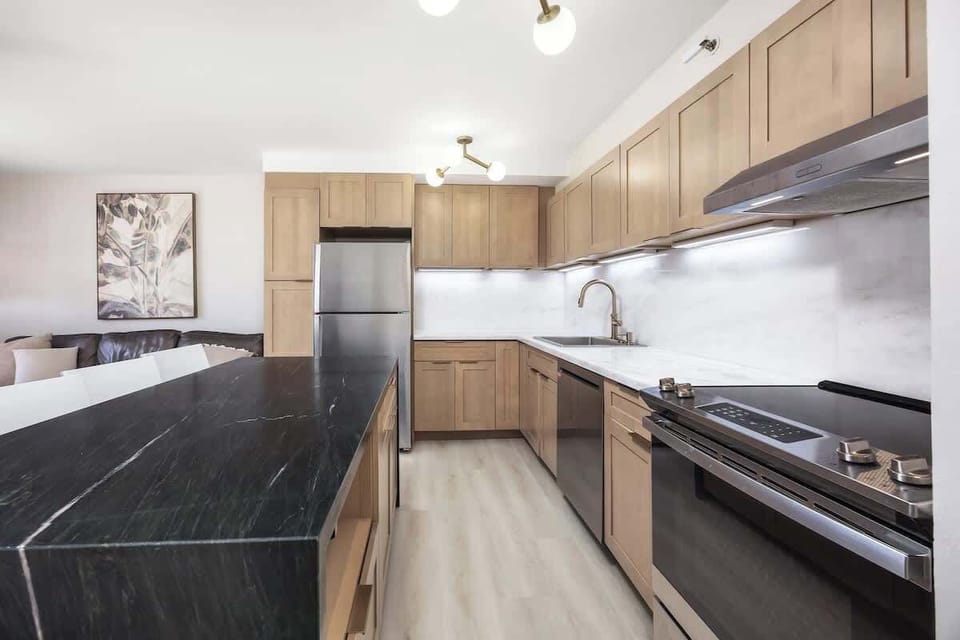 Whip up a delicious meal in your fully-equipped kitchen, which boasts beautiful light wood cabinetry, sleek stainless steel appliances, and a spacious dark marble countertop for prepping and serving!
