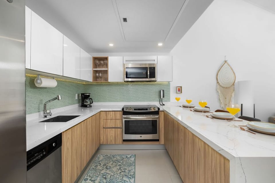 Your modern kitchen invites culinary creativity with sleek white counters, warm wood cabinetry, and full appliances—perfect for cooking meals together or enjoying morning coffee at the breakfast bar.