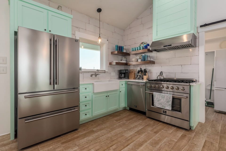 Your gourmet kitchen beckons with mint-green cabinets and stainless steel appliances, where morning coffee and home-cooked meals become vacation highlights.