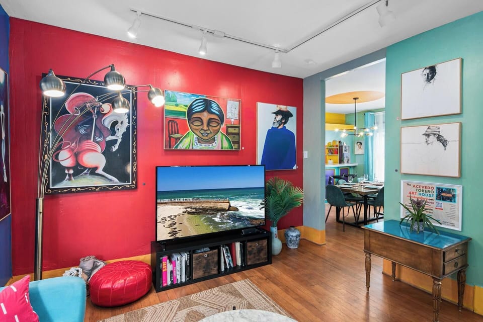 Vibrant blue and red living room with smart TV and original paintings