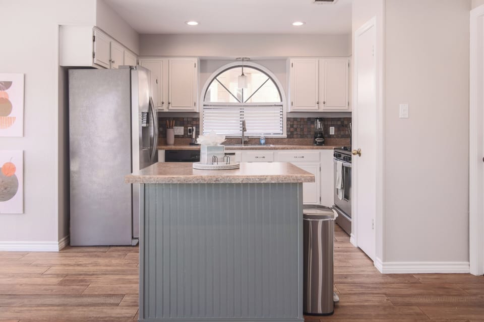 Enjoy the practicality of this kitchen, featuring a sleek countertop, a refrigerator, and plenty of kitchen cabinets for ample storage. A perfect setup for preparing meals with ease and convenience.