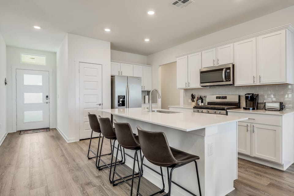 Kitchen features an island with 4 barstools.