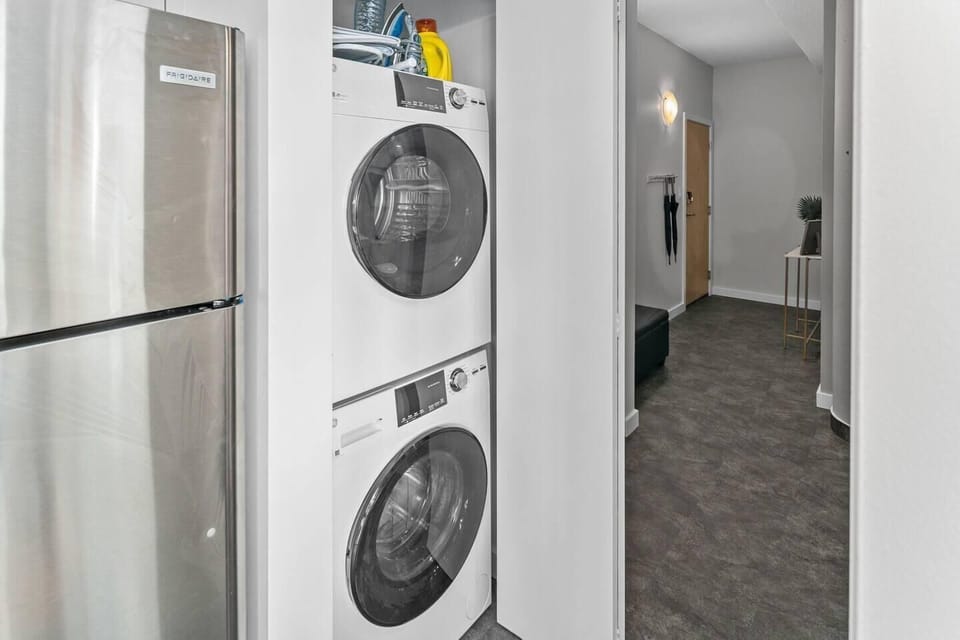 Dedicated utility area featuring a full-sized, stacked washer and dryer in the hallway closet.