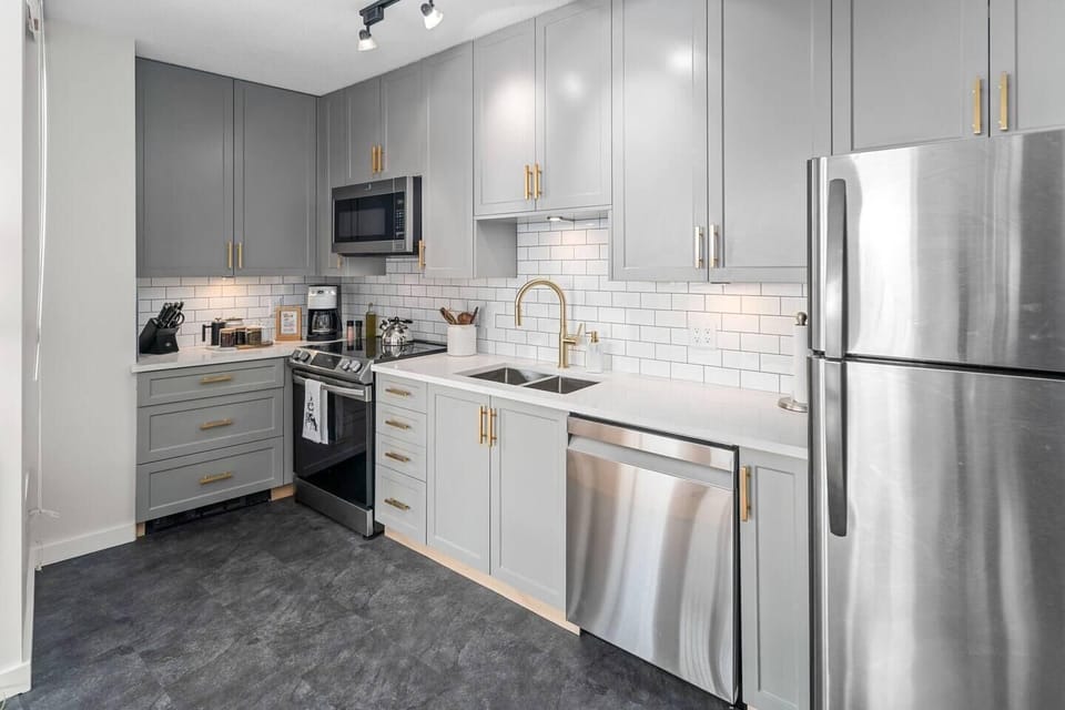 Executive kitchen equipped with full-sized stainless steel appliances, built-in microwave, and tile backsplash.