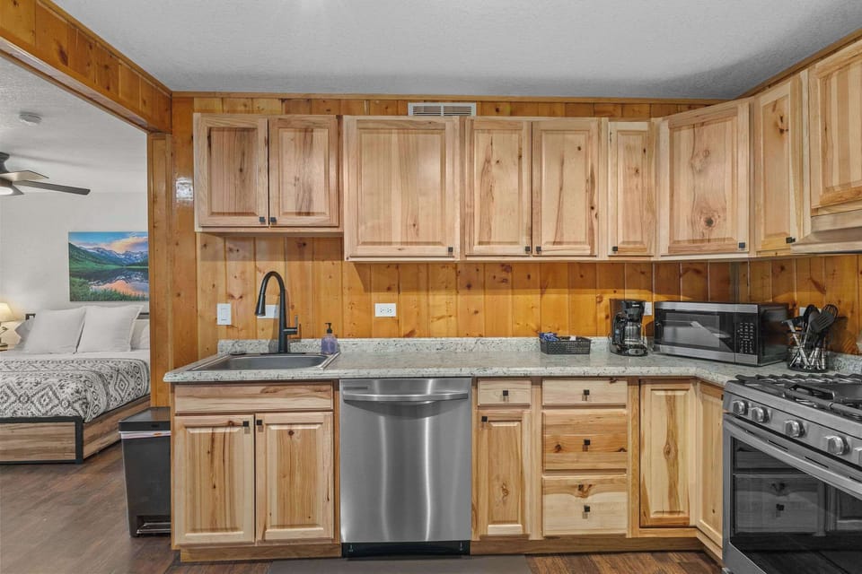The kitchen has full sized stainless steel appliances including a gas stove, dishwasher, refrigerator and microwave.