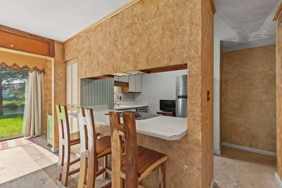 The kitchen area has an open breakfast bar with three uniquely wood crafted barstools.