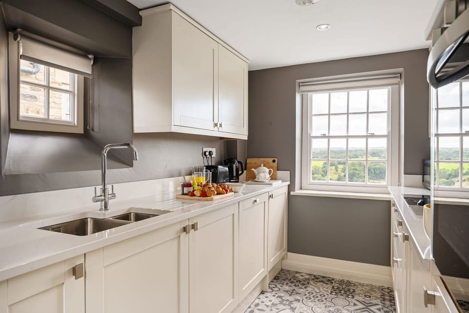 Maison Cottage kitchen with white cabinetry, modern appliances and window views across the countryside