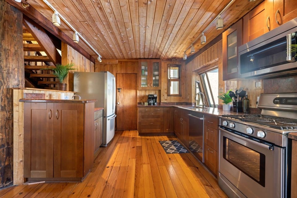 Spacious galley kitchen with stainless fridge, gas range, and staircase access.