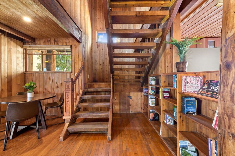 Enjoy cozy meals at the round dining table while admiring the rustic wooden staircase and built-in bookshelf.