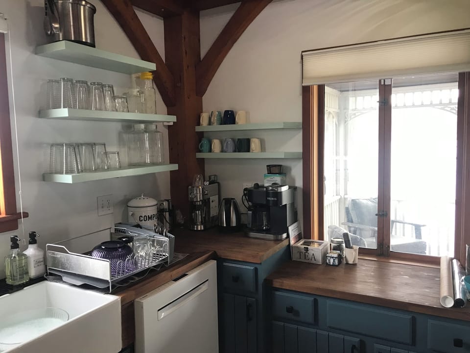 Coffee station in kitchen with window opening onto screened porch