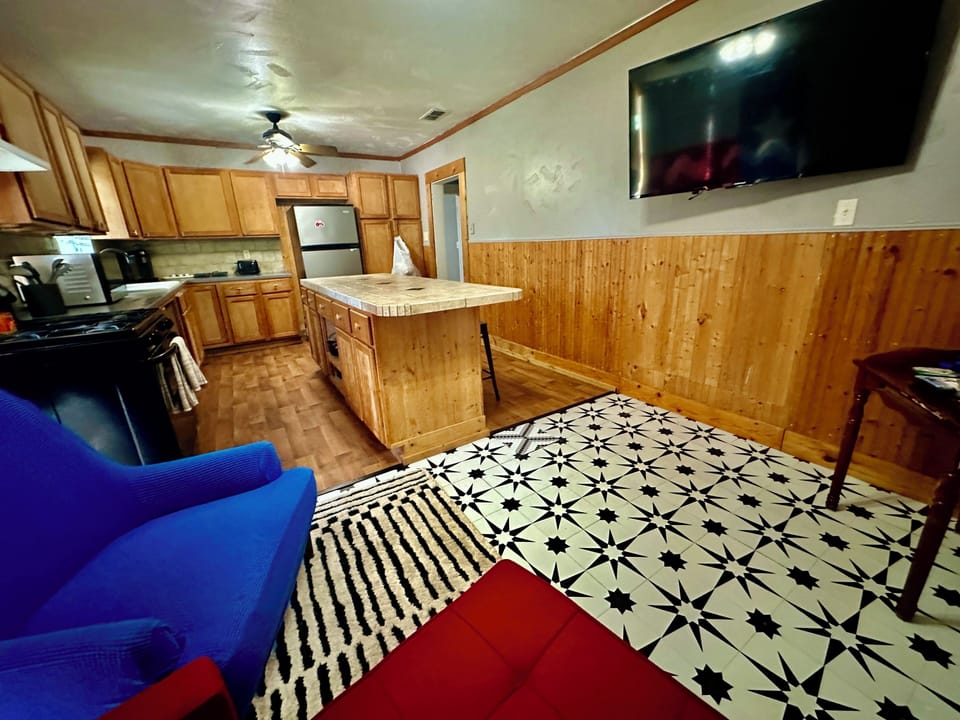 Relax in your open-concept living space featuring a full kitchen, bright seating area, and flat-screen TV. The tiled floors and warm wood accents create a cozy retreat after your adventures.