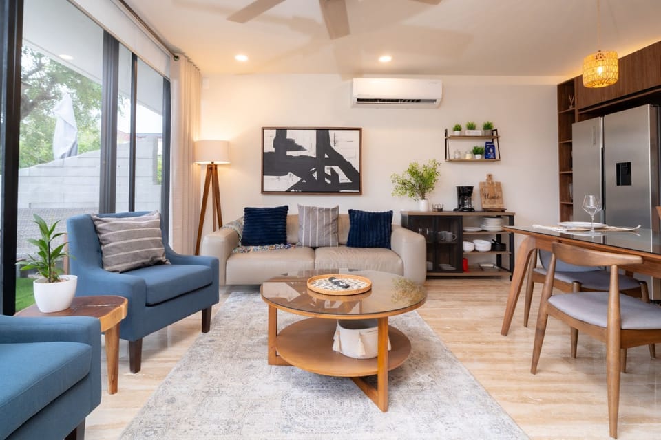 Modern living room with blue and grey tones, cozy seating, and natural light.
