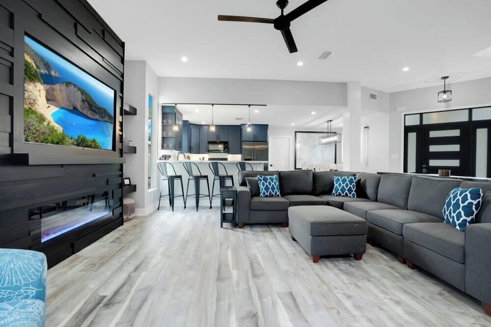 Modern living room with a large sectional sofa and a built-in fireplace under the television.