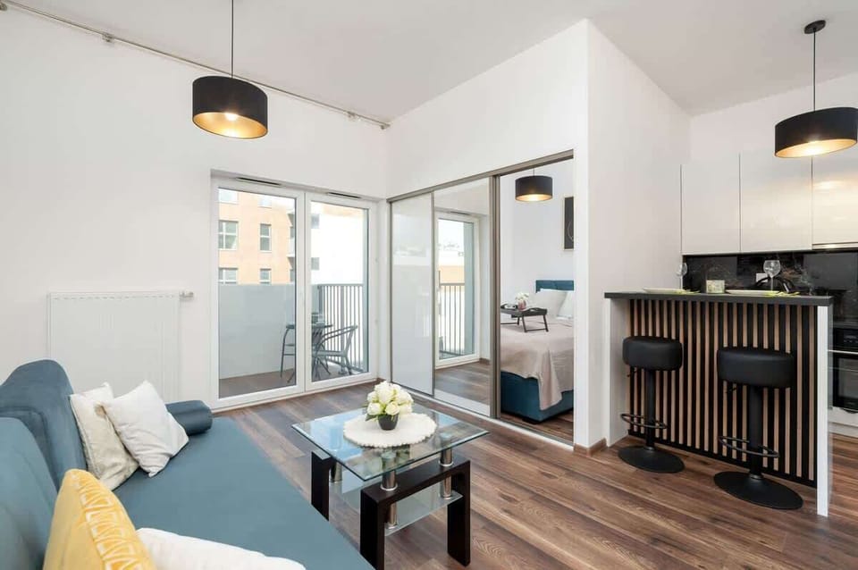 A bright and welcoming living room featuring a stylish sofa for one, a coffee table, and tasteful artwork. Large windows let in plenty of natural light, creating a relaxing atmosphere after a day of exploring the city.

