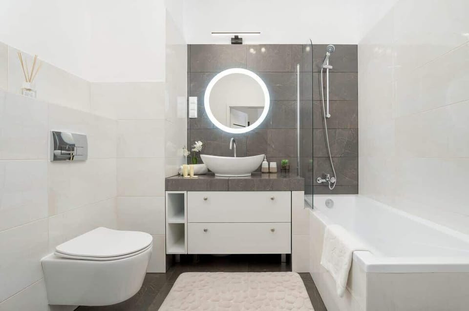 Bright, clean bathroom with a combination bathtub and shower, stylish vanity with LED mirror, and modern fixtures. Towels and basic toiletries provided.

