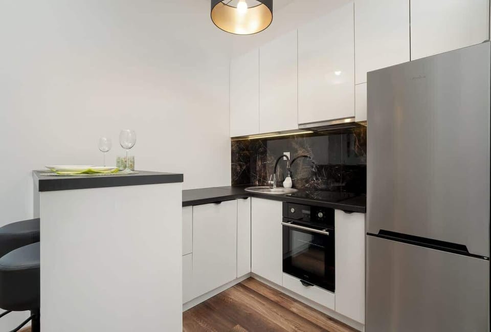 Compact kitchen with white cabinets, built-in sink, electric stove, oven, fridge, and upper glass cabinets.

