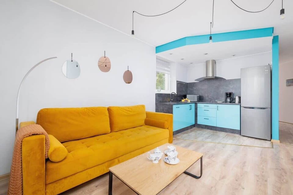 In this cheerful living room, a vibrant yellow sofa and turquoise kitchen cabinets make the space feel fresh and energetic.