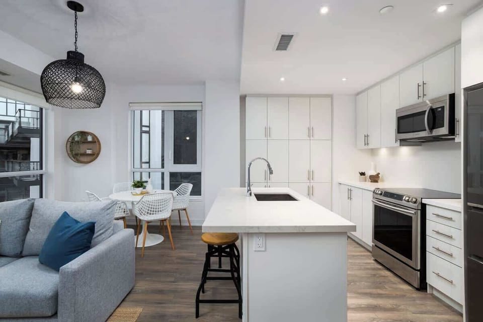 Modern open concept living space featuring a fully equipped kitchen with large fridge and stove