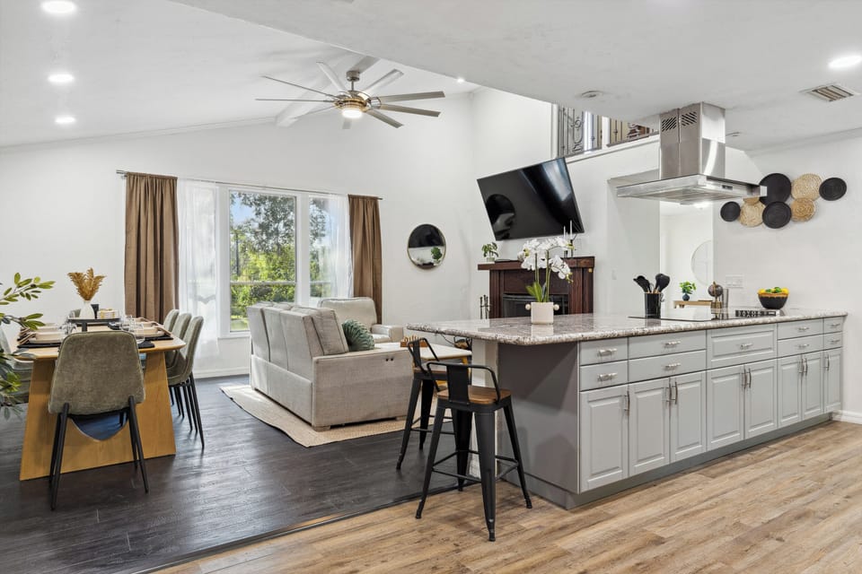Elegant dining area: wood table seats 8+, green velvet chairs & kitchen view