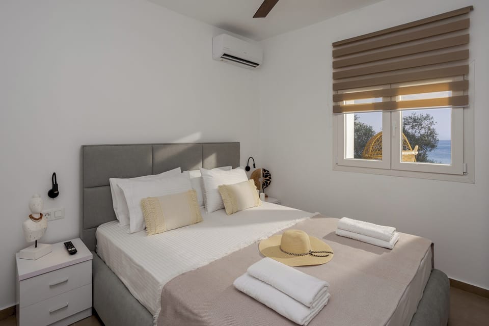 Same bedroom from a new angle with window view of sea and trees
