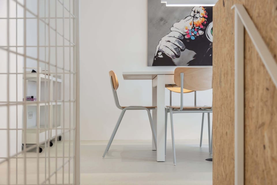 A clean dining setup framed by white grid lines and a bold art piece — blending Scandinavian calm with creative energy.