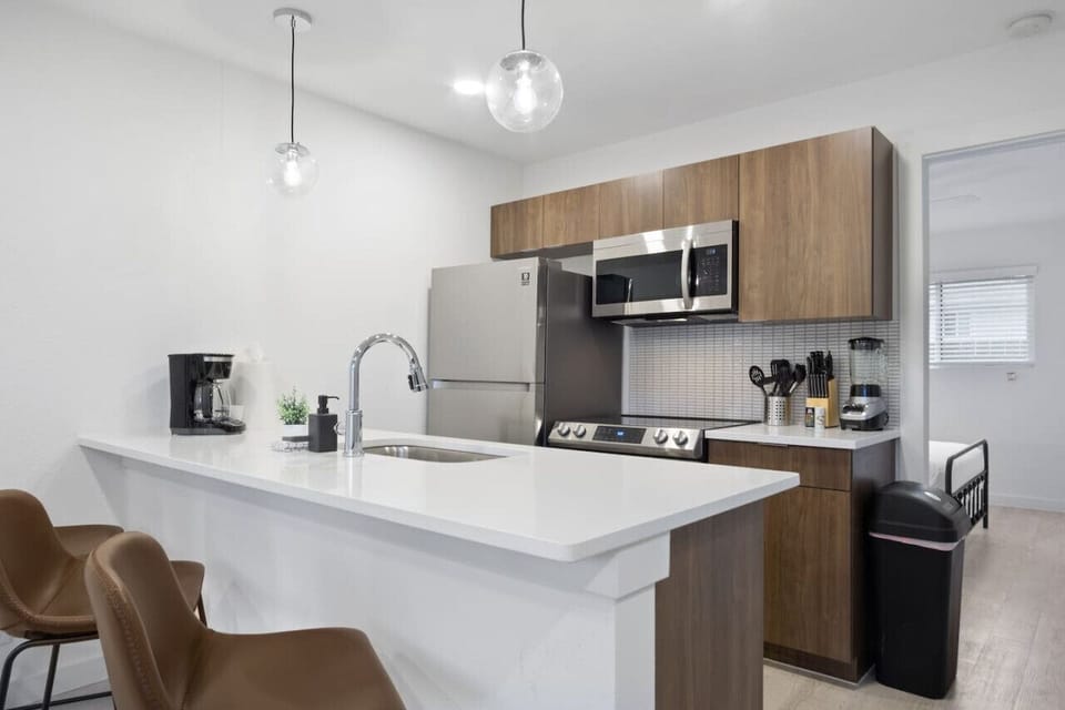 Prepare meals in this modern, fully-equipped kitchen featuring stainless steel appliances and a spacious island with bar seating. The open layout makes it easy to cook and entertain, ensuring a delightful culinary experience during your stay.