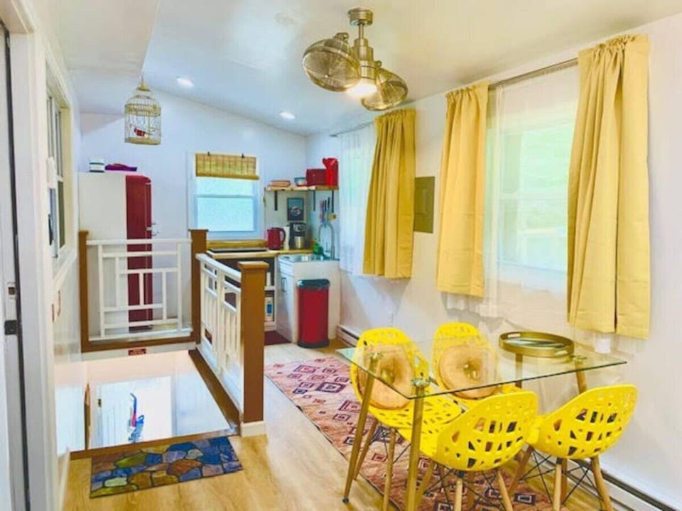 Open living space with kitchenette, charming double-headed fan, and staircase leading to the private entrance.
