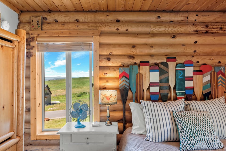 Relax in rustic charm! Cozy up in this log cabin bedroom featuring a comfy queen bed and Bear Lake-inspired paddles