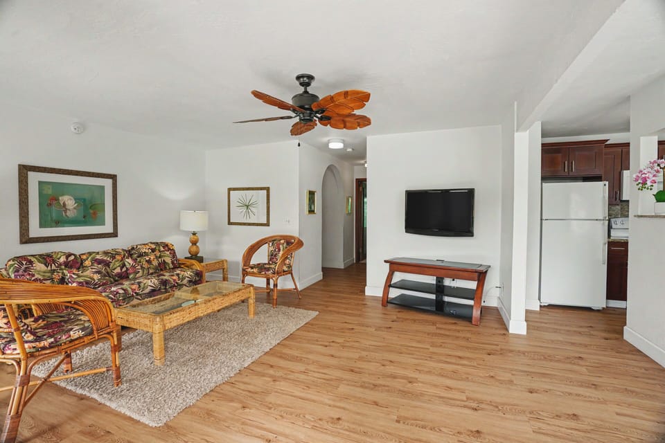 Relax in your spacious living room with tropical-style furnishings, ceiling fan, flat-screen TV, and open flow to the fully-equipped kitchen—perfect for unwinding after island adventures.