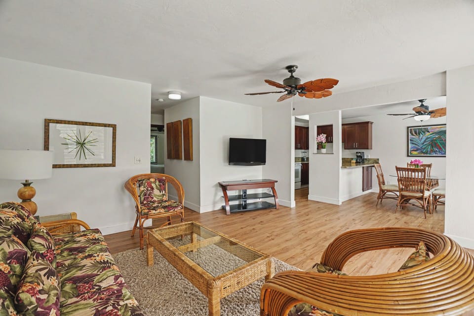 Relax in your spacious open-concept living area with tropical-style furnishings, ceiling fans to keep you cool, and seamless flow into the fully equipped kitchen and dining space.
