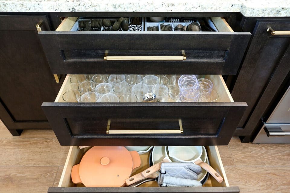 This kitchen boasts organized, deep drawers for silverware, glasses, and cookware, ensuring easy access and a tidy space.