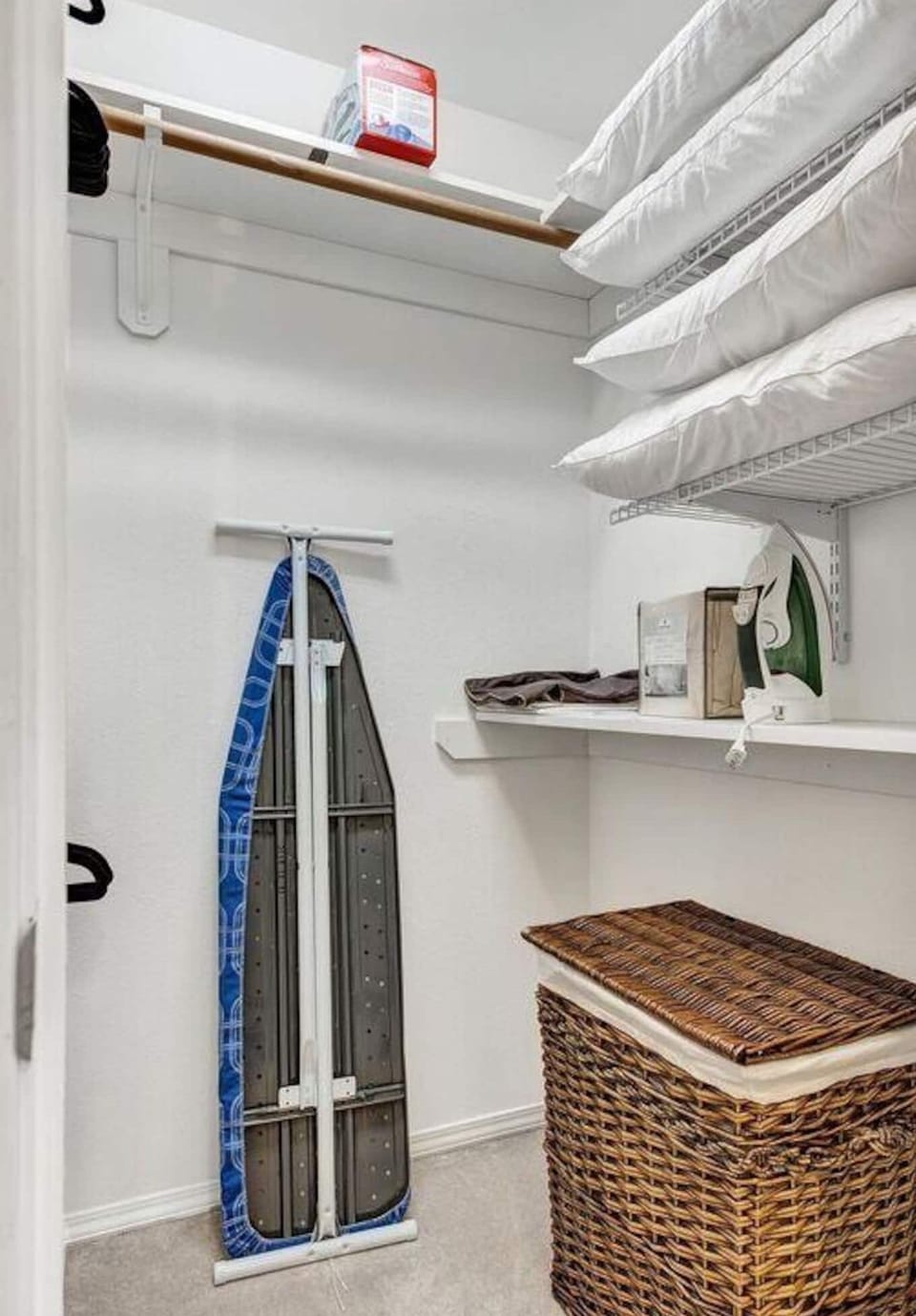 Primary bedroom walk-in closet includes iron and ironing board, extra pillows.