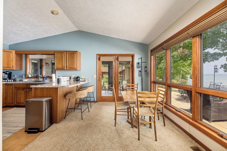 Open kitchen & dining area w/ wood cabinets, breakfast bar & wall of windows framing the lake.