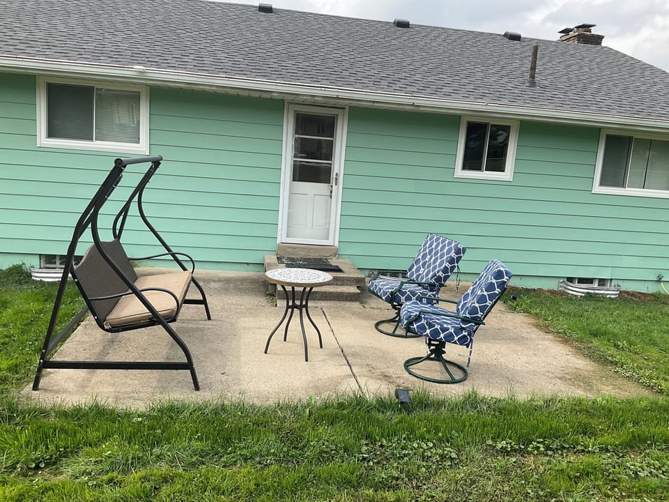 Outdoor patio with swing, table, and chairs.