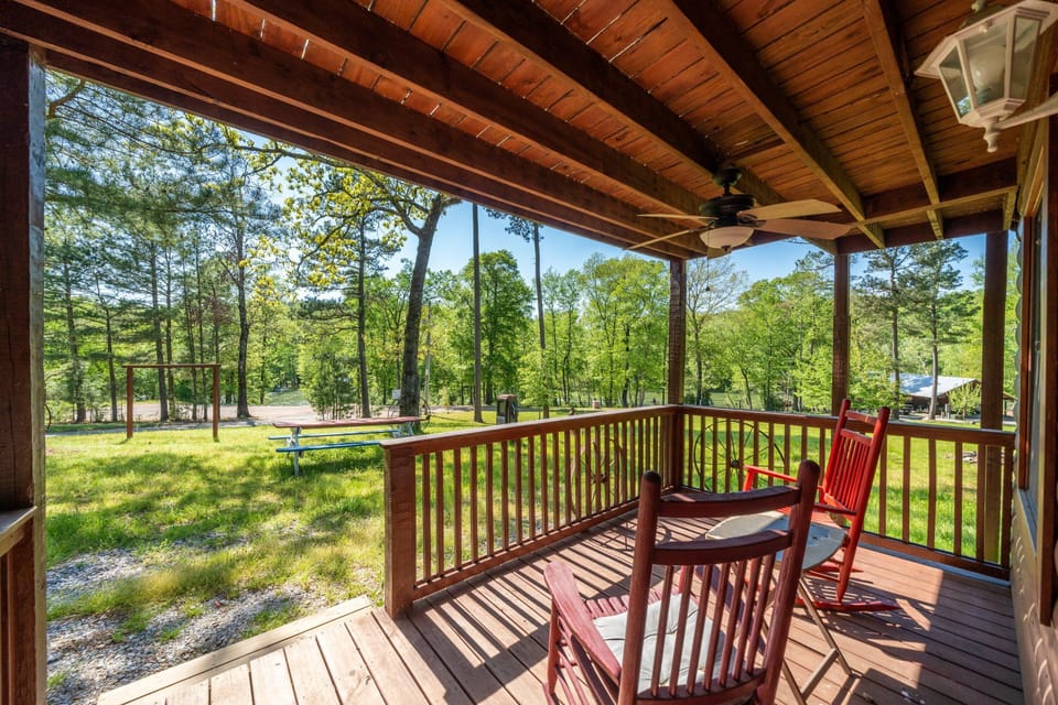 Two red rocking chairs provide a shaded place to enjoy the lawn and wooded surroundings.