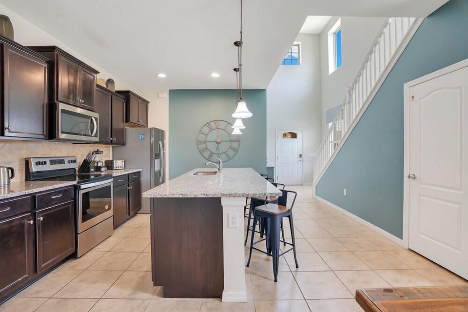 Modern kitchen with granite island and stainless steel appliances.
