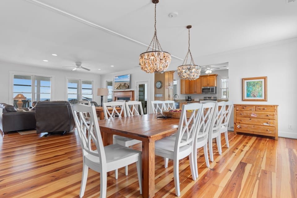 Gather around your elegant dining table under sparkling chandeliers, where polished hardwood floors and ocean views create the perfect setting for memorable meals.