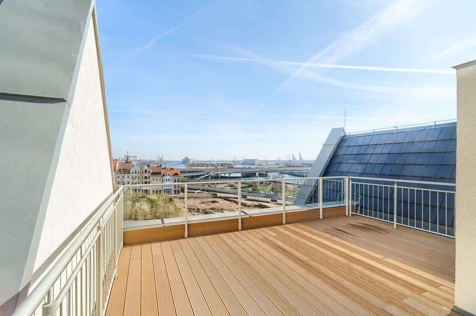 Rooftop terrace with wooden decking and city view.