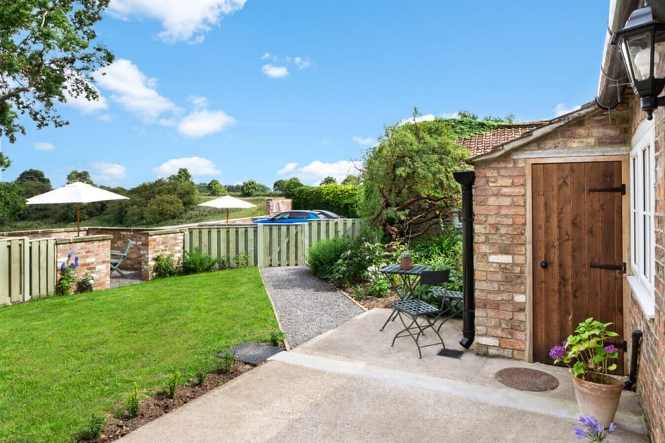 Enjoy the garden with seating and a bench, connecting to the kitchen, and take in the view of the terrace and treeline beyond – a perfect North Yorkshire retreat.