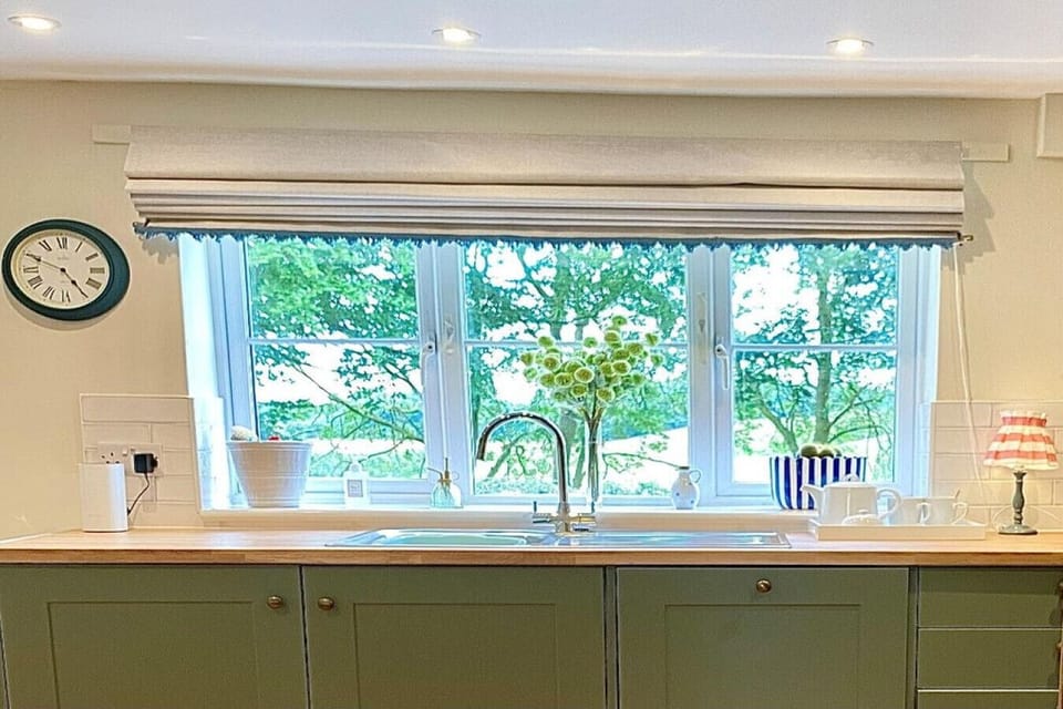 Cook and dine in the charming green kitchen with a tranquil view of the tree-lined countryside – a perfect setting for your Yorkshire stay.