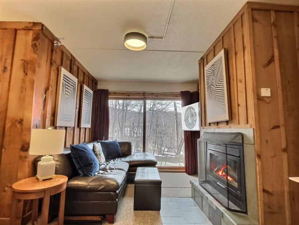 Living area with cozy sofa and wood paneled walls. (Fireplace Not Available)