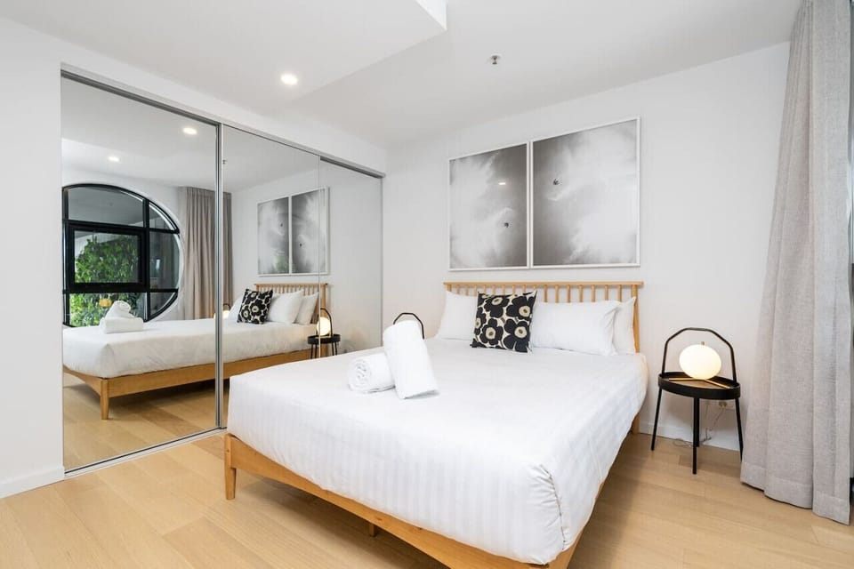 Queen size bed with professionally laundered linens, complemented by a stylish large round window and a cosy, inviting atmosphere.