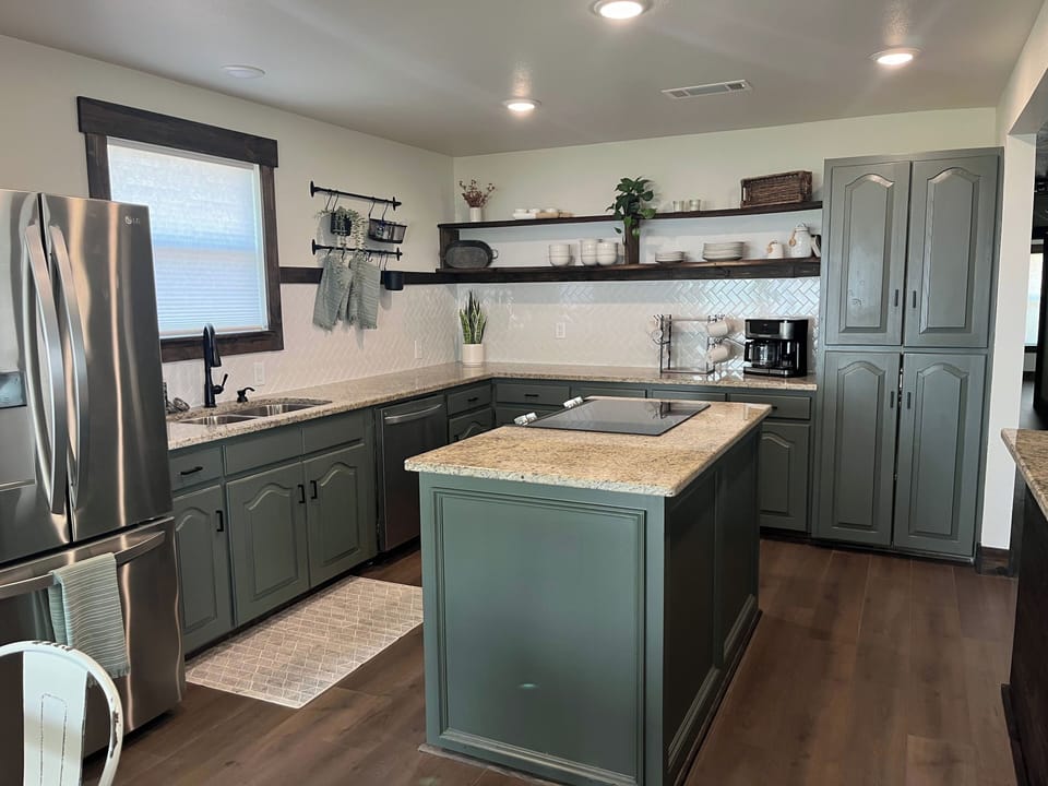 Large open kitchen with island cooktop and adjacent bar with more seating. 