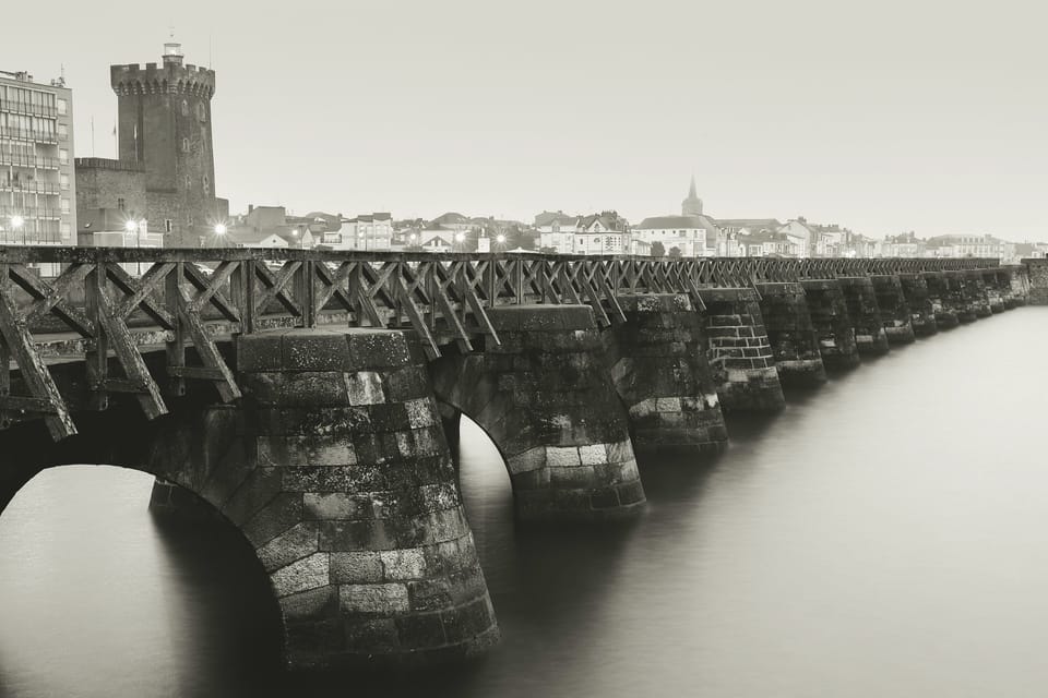 Port des Sables d'Olonne spanning a river with a medieval tower and town skyline beyond