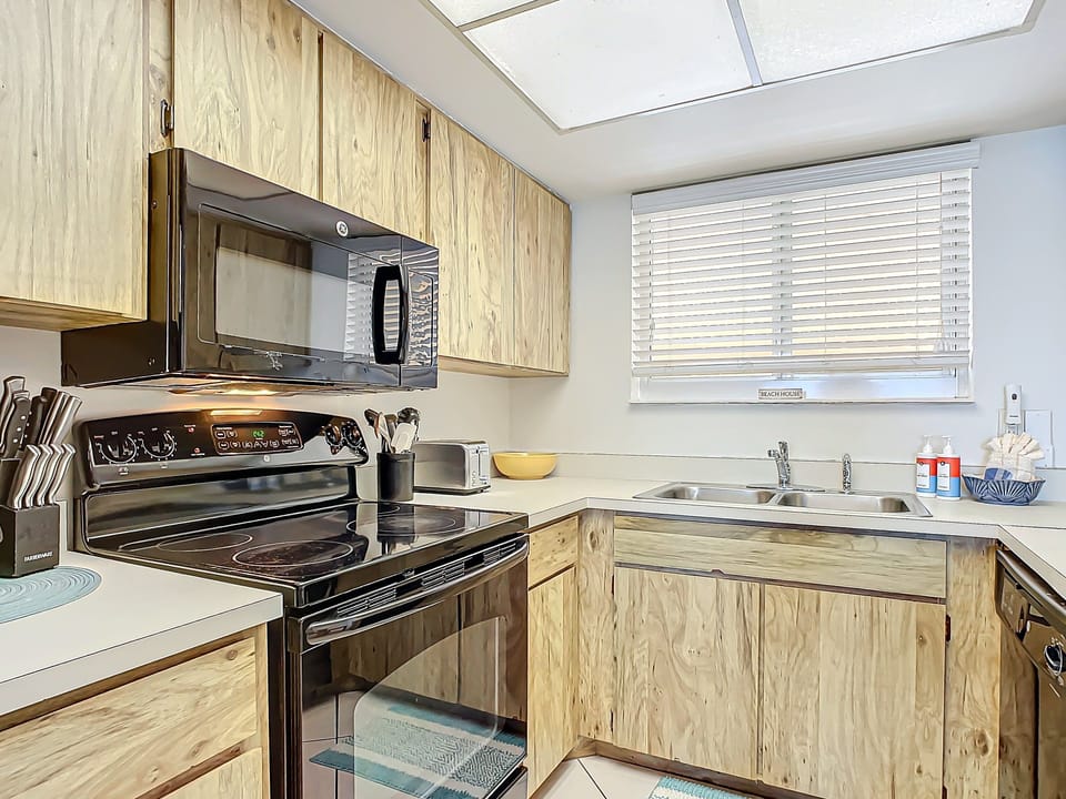 Fully equipped kitchen featuring sleek black appliances, natural wood cabinets, and ample counter space for cooking.