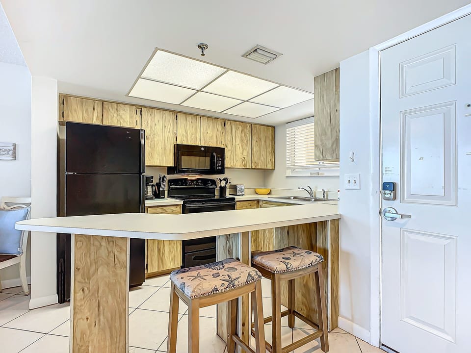 Kitchen with black appliances, wood-accented cabinets, and ample counter space designed for convenience and style.