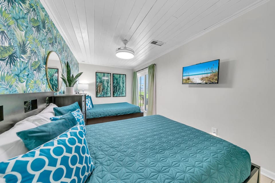 Drift off in your tropical twin bedroom, featuring lush palm wallpaper and ocean-inspired blues for the perfect beach getaway.