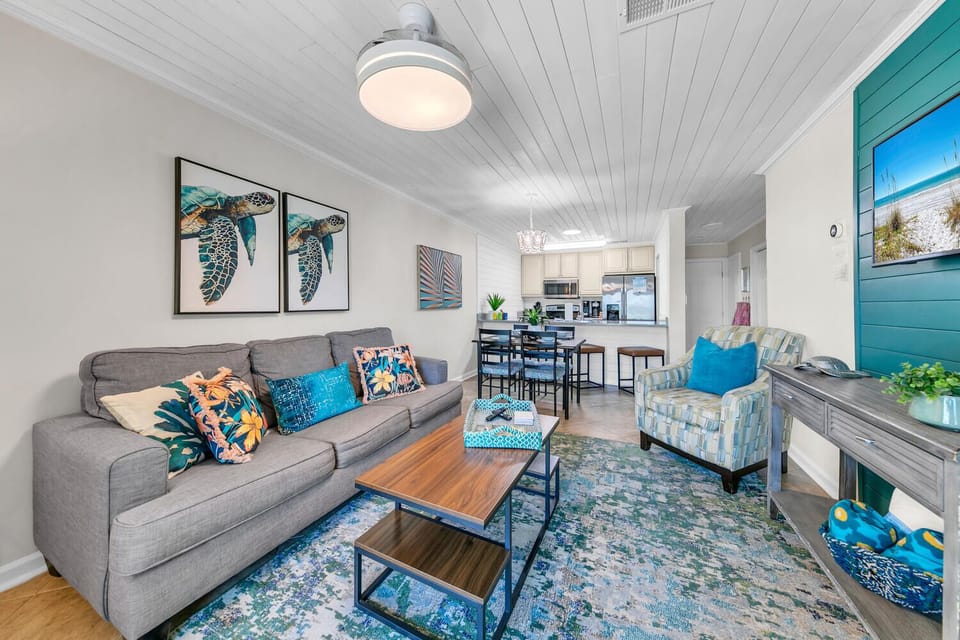 Relax in your coastal-inspired living space with ocean-themed art and comfy seating flowing into your fully equipped kitchen.