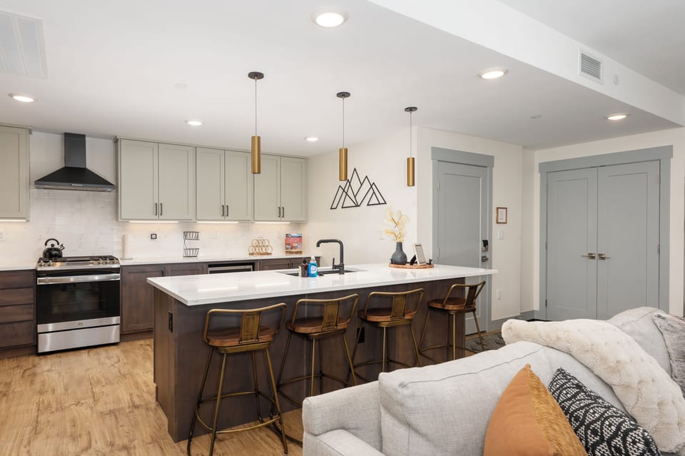 - Bright and modern, this open concept kitchen features bar seating for four - Pendant lighting, mountain wall art, and a neutral palette complete the space - Enjoy cooking while staying part of the fun in this social setup